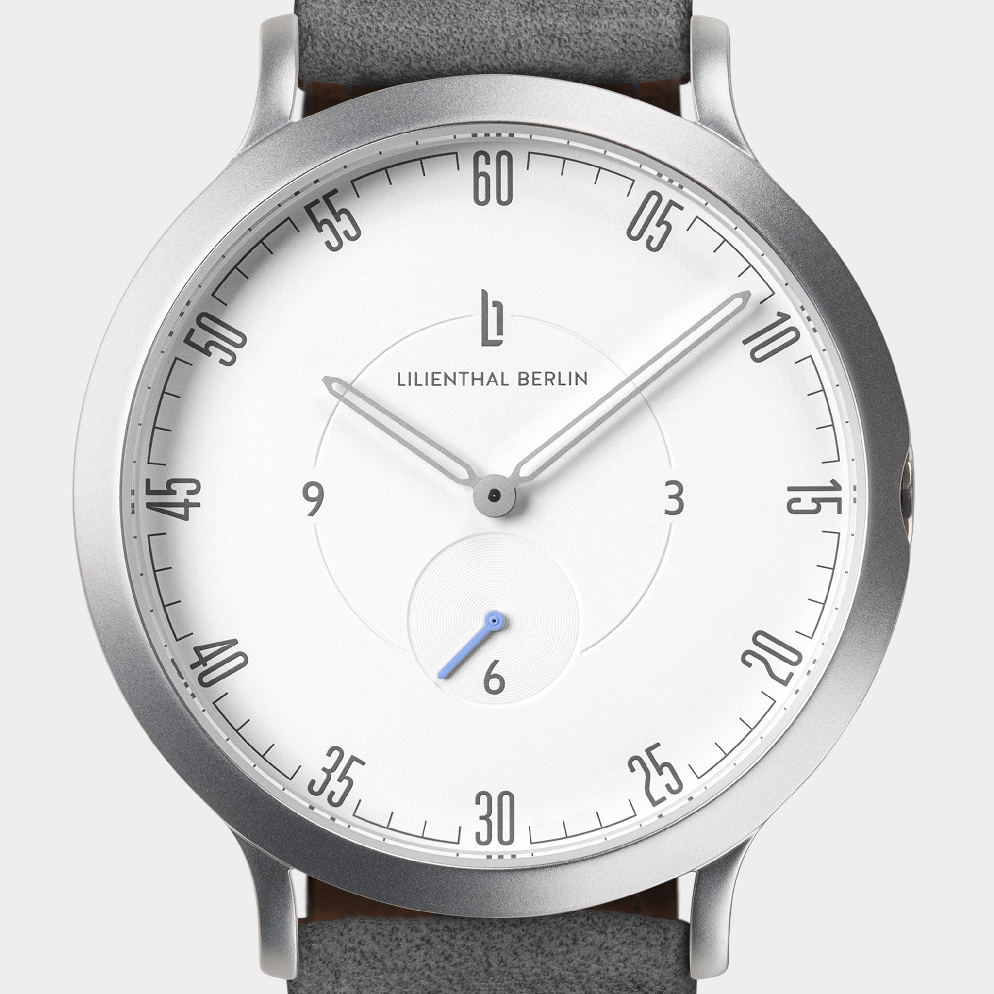 Minimalist silver wristwatch with white dial, black numerals, and grey leather strap