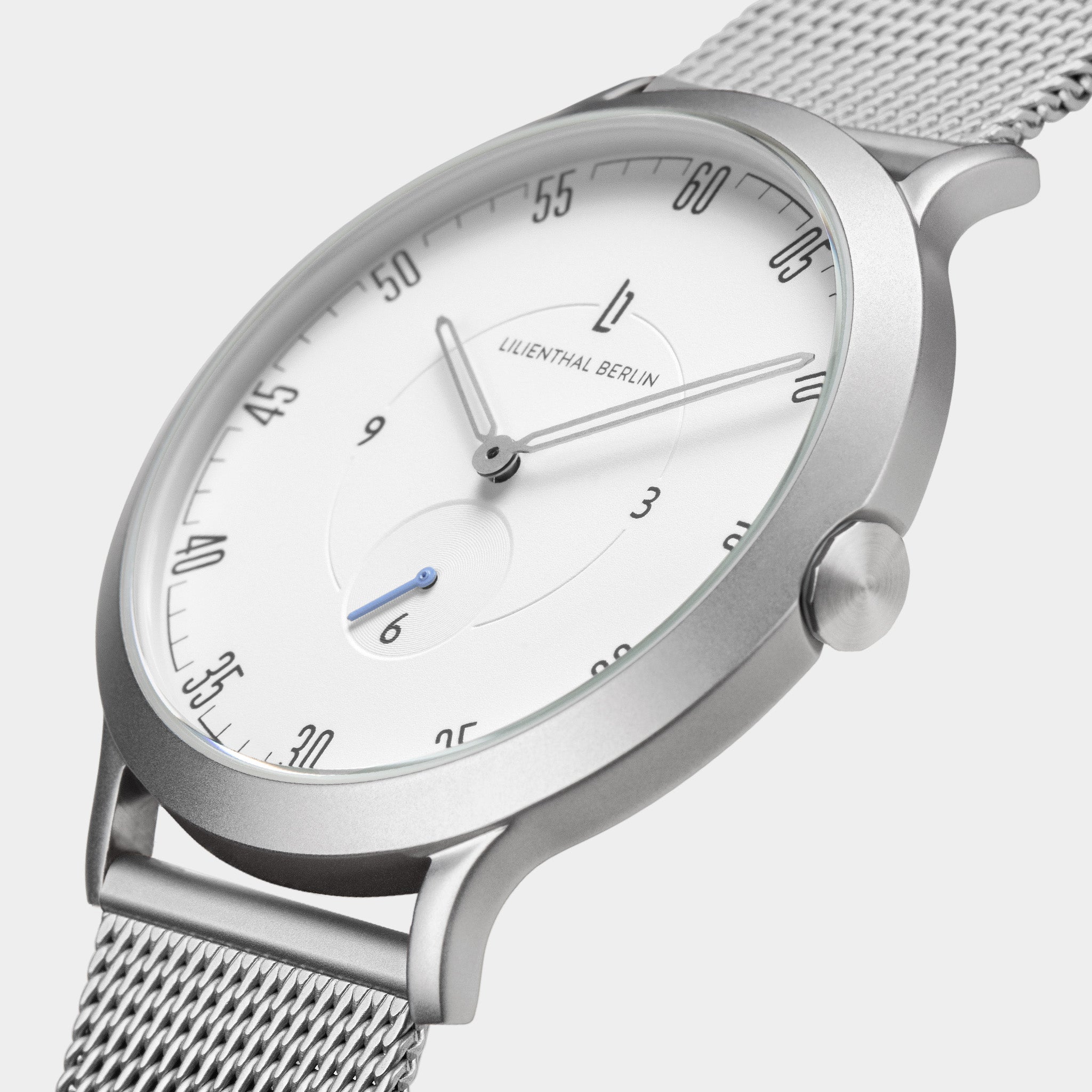 Minimalist silver mesh watch with white dial and black markers, close-up side view