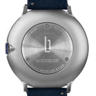 Stainless steel watch case back with engraved logo, blue crown, and navy strap