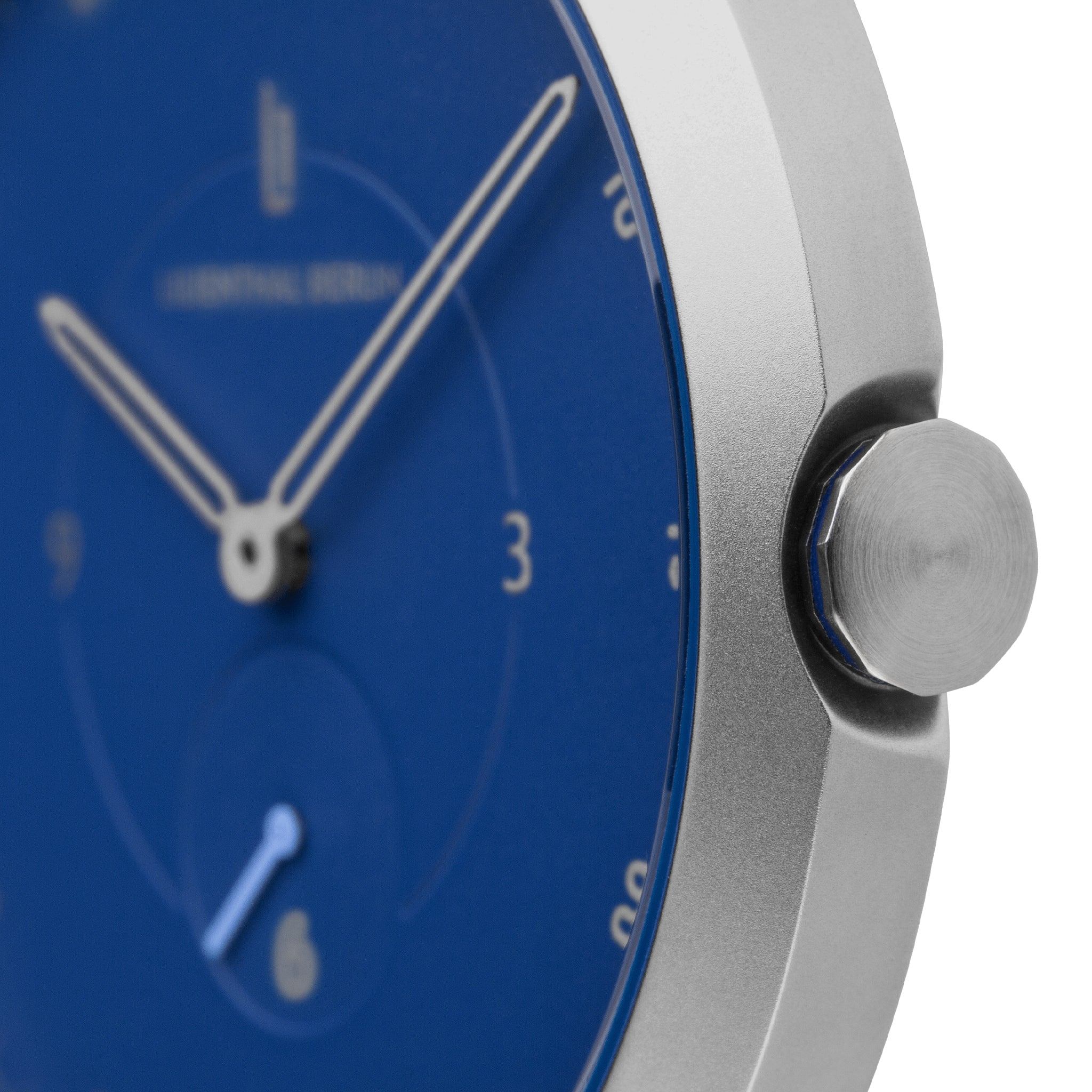 Close-up of minimalist blue watch face with silver case and visible crown