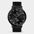 Black minimalist wristwatch with a black leather strap and sleek dial design
