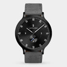 Minimalist black watch with grey leather strap, black dial, and white markers