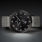 Minimalist black watch with grey leather strap, modern dial, and distinctive white markers
