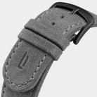 Close-up of grey suede watch strap with black buckle and visible stitching