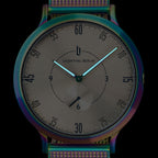 Minimalist analog watch with iridescent case and mesh strap, black dial, luminous hands