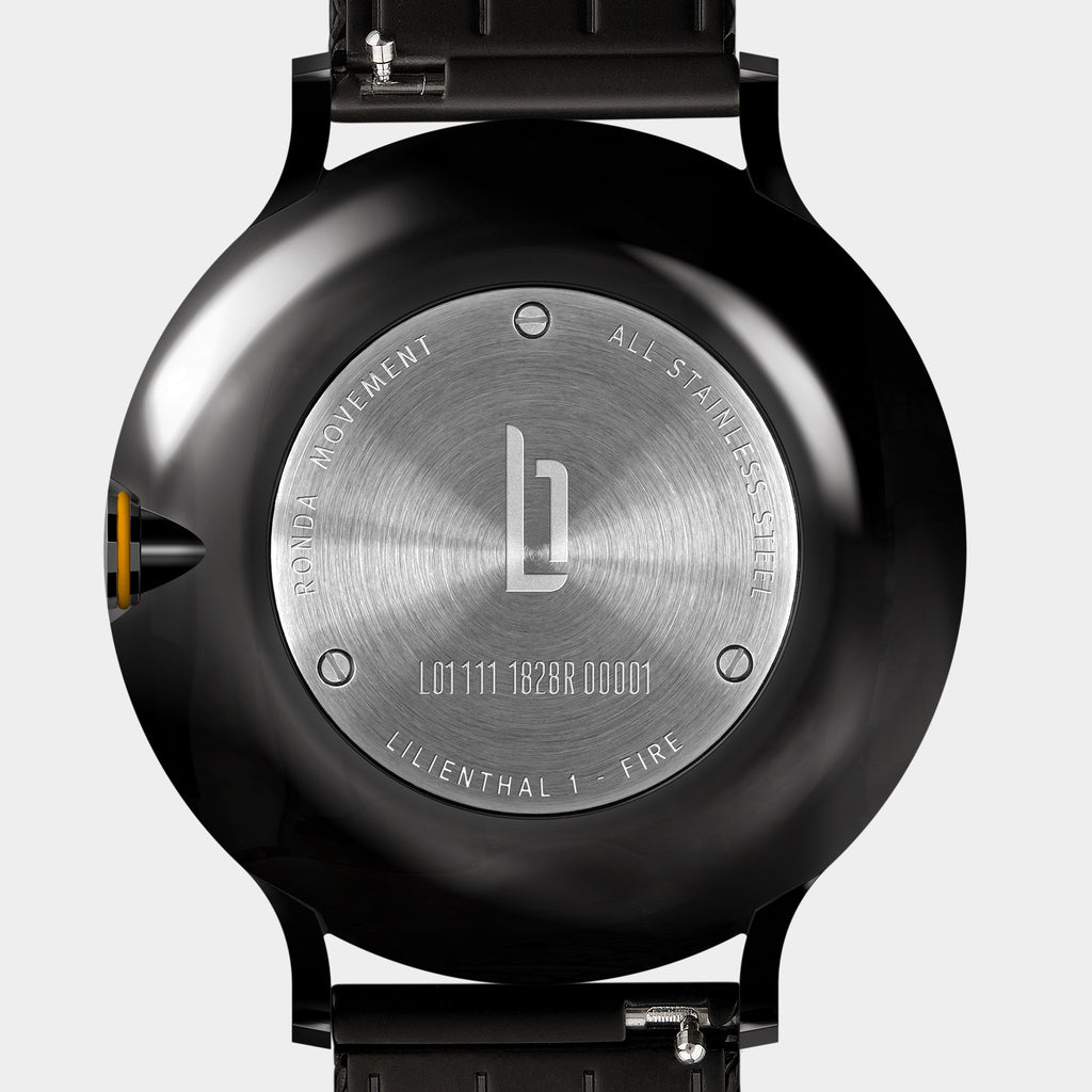 Close-up of stainless steel watch case back with engraved details and black strap