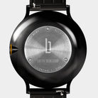 Close-up of stainless steel watch case back with engraved details and black strap