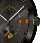 Close-up of black watch face with orange accents and brushed metal finish
