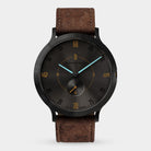 Men's black dial wristwatch with brown leather strap, minimalist design, blue hands.