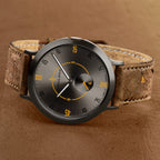 Modern minimalist watch with brown textured strap, black dial, and orange accents on numbers