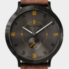 Close-up of a modern wristwatch with black dial, yellow numerals, and brown leather strap