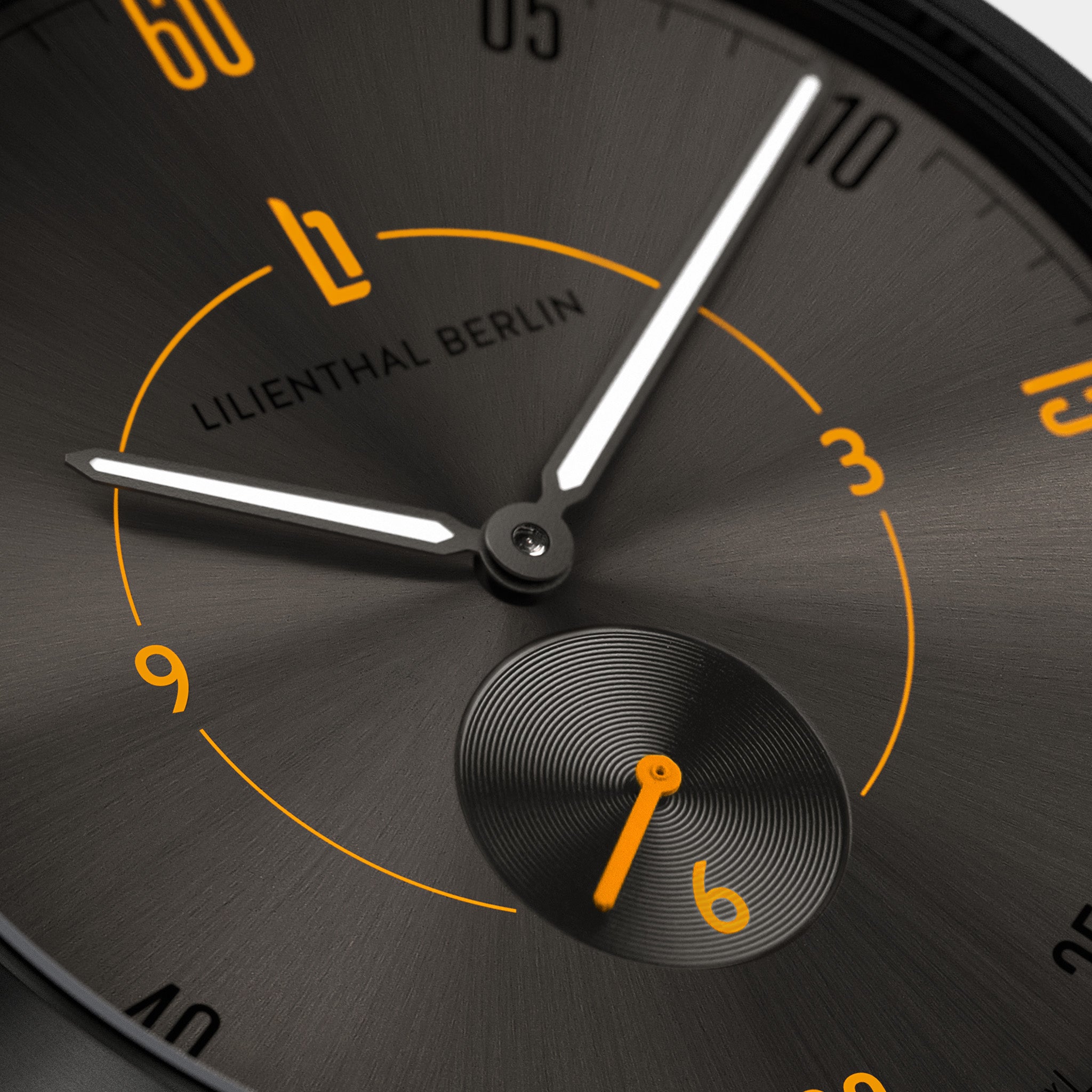 Close-up of a modern black watch face with orange accents and luminous hands