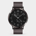 Minimalist black wristwatch with mesh band, round dial, and silver hour markers on white background.
