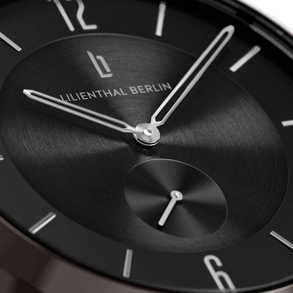Close-up of a minimalist black watch face with silver hands and hour markers