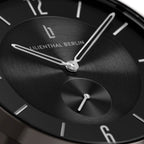 Close-up of a minimalist black watch face with silver hands and hour markers