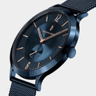 Blue minimalist wristwatch with mesh strap, rose gold accents, and sleek modern design.