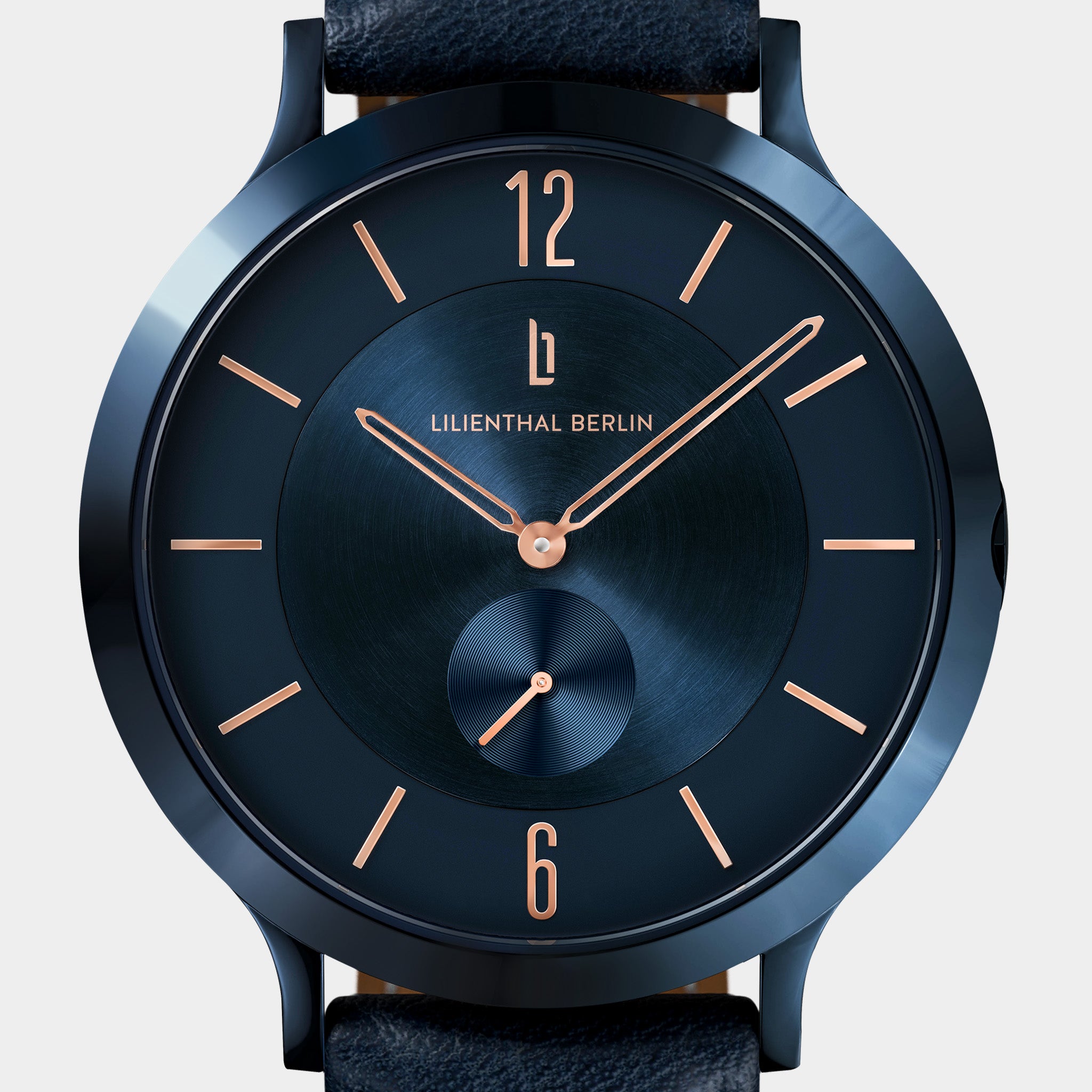 Minimalist blue wristwatch with rose gold hands and numerals, black leather strap