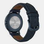 Close-up of a watch back with stainless steel case and navy leather strap