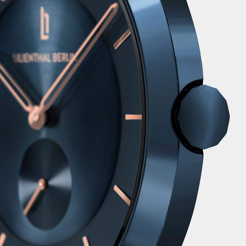 Close-up of minimalist blue watch with rose gold hands and hour markers on brushed dial